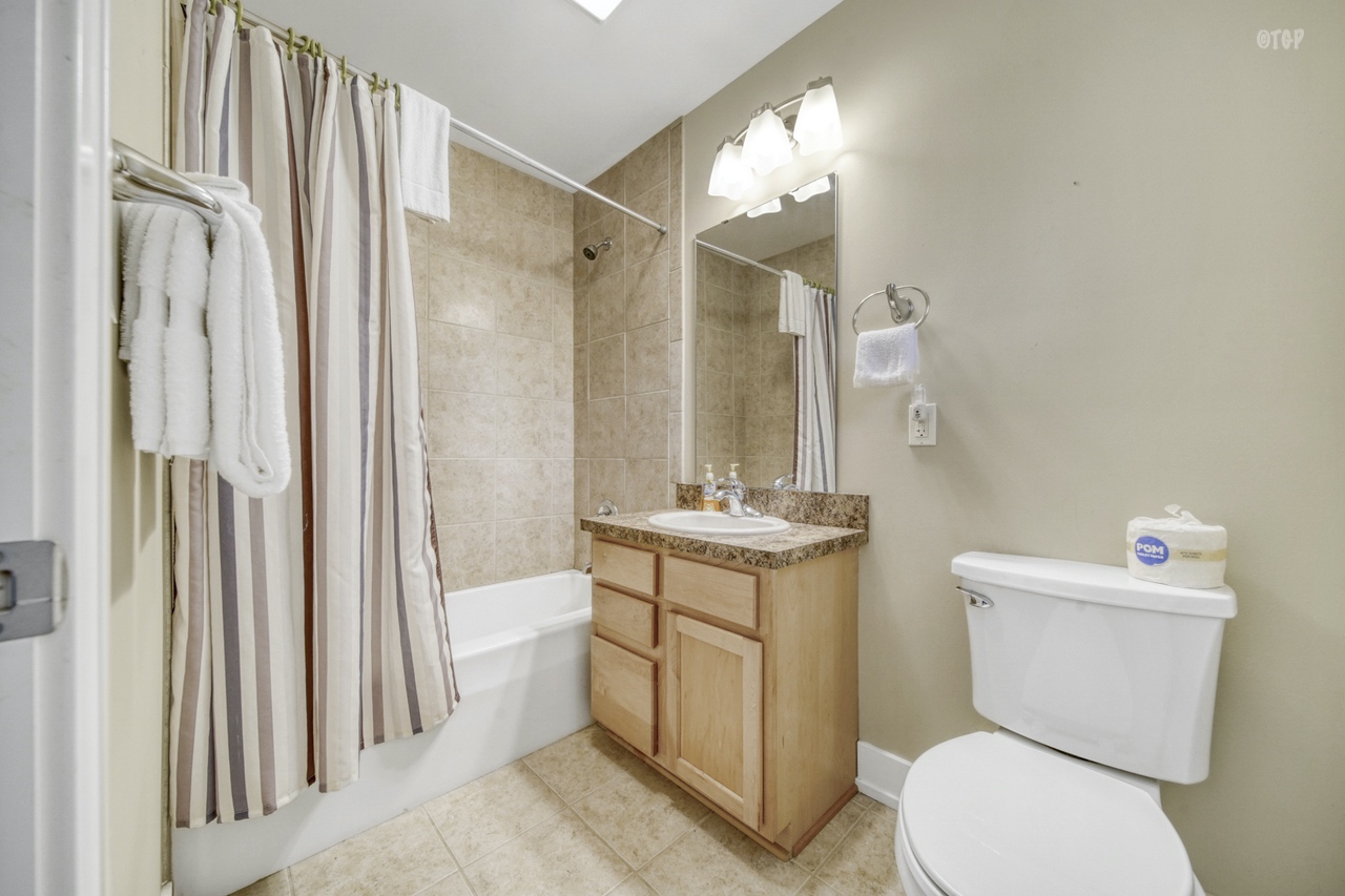 The 1 bed 1.5 bath in Northern Lights Condo Resort Unit 13 features a shower/tub and vanity.
